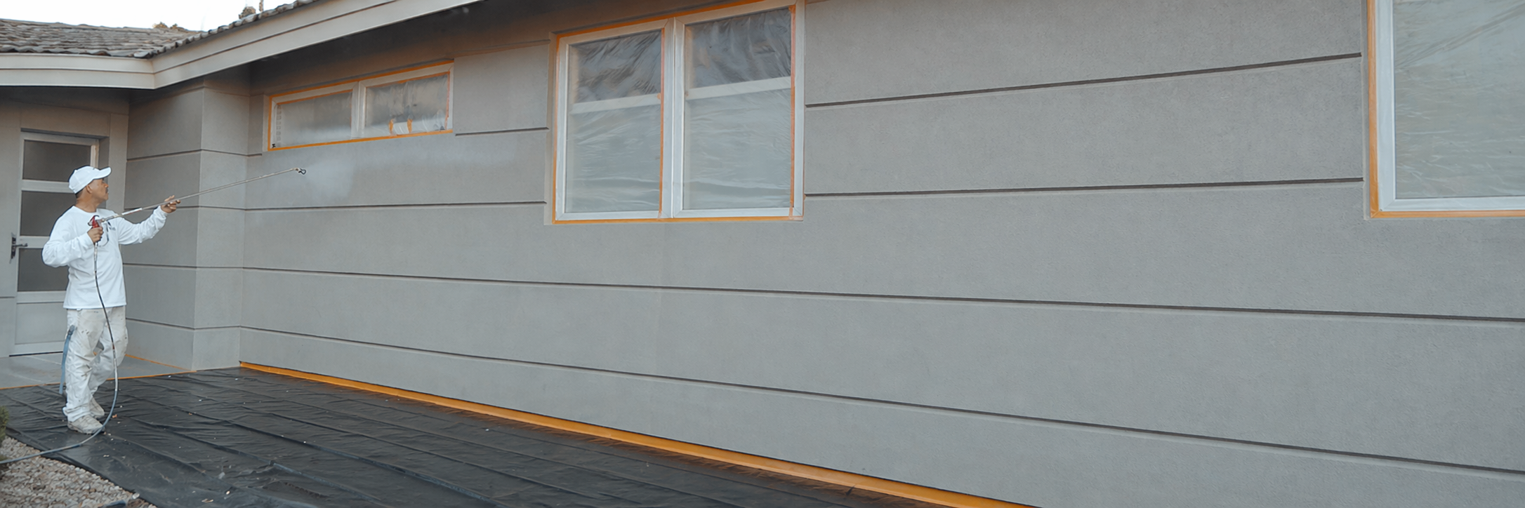 Man spray painting a house 1 how much does it cost to paint a house in denver in 2026?